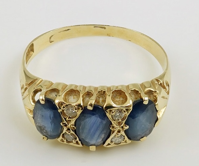 An Edwardian 15ct gold and three stone oval cut sapphire set half hoop ring, with diamond chip spacers, size Q, gross weight 2.4 grams. Condition - poor to fair